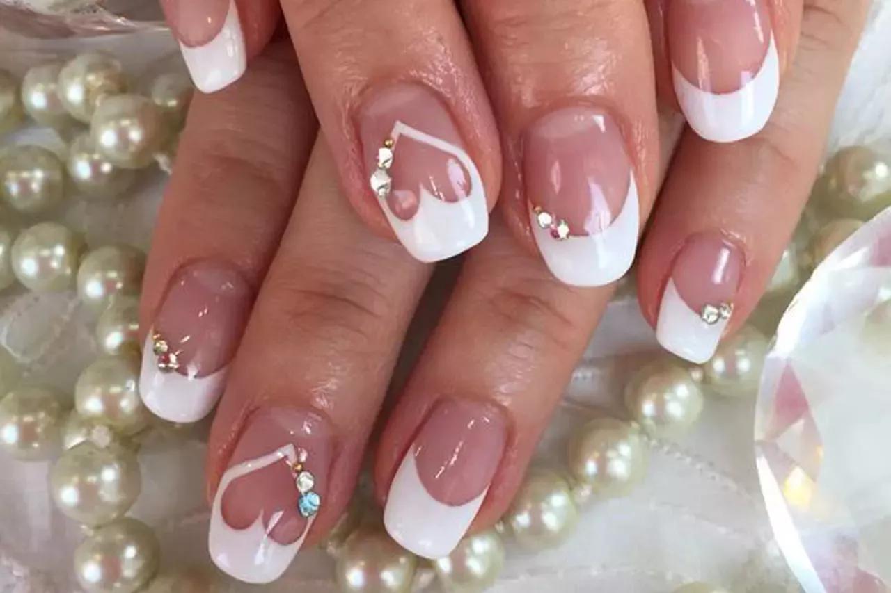 Brilho e sofisticação ao alcance das mãos! Estas unhas brancas com pedrarias e strass adicionam um toque de glamour a qualquer look.